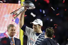 Tom Brady smiling as he hoists the Vince Lombardi Trophy