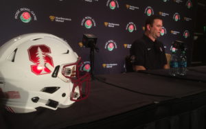 Stanford helmet in the foreground, with Mike Bloomgren at the podium to the right of the helmet